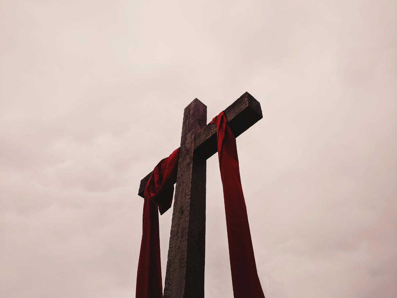 Wooden cross with red cloth draped over.