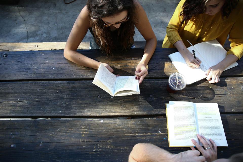 Group studying books outdoors at a table